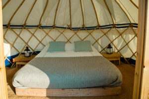 A bed with pillows and lanterns inside a furnished yurt.