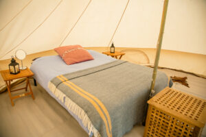 Bed and bedside tables inside a furnished bell tent