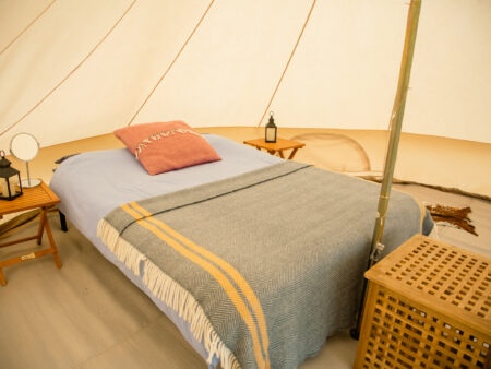 Bed and bedside tables inside a furnished bell tent