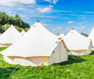 White bell tents on grass under a blue sky.