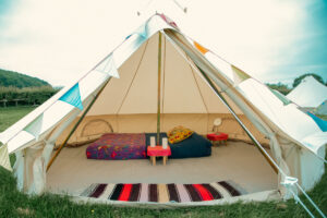 Interior of a bell tent with low bedding, cushions, and small side tables.