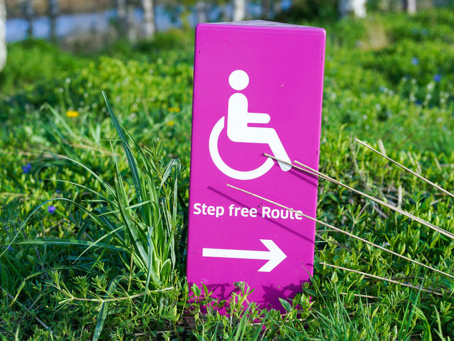 Pink sign with a wheelchair symbol and arrow pointing right for a step-free route.