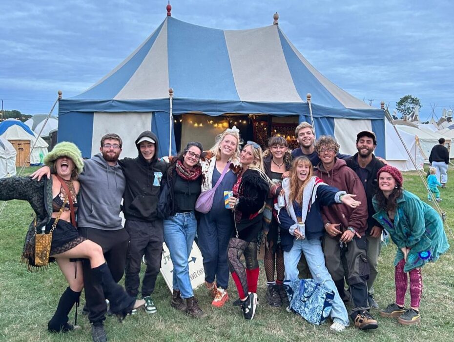 A group of people posing in front of a large blue-and-white festival tent.